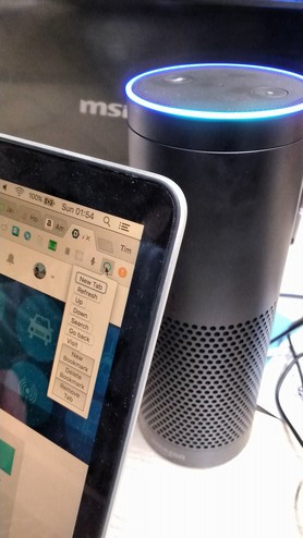 A photo of an Amazon Echo, behind a laptop displaying the Chromelexa plugin