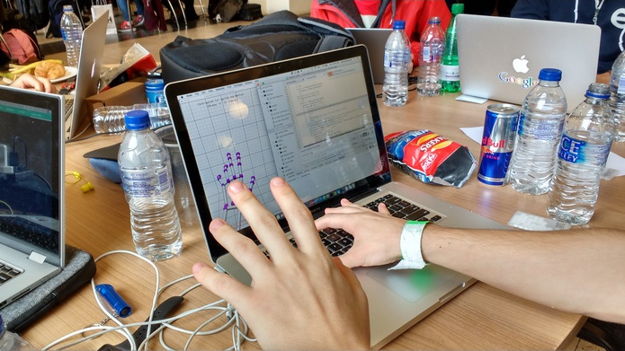 A laptop displaying the Atom text editor and a graphic showing hand movement. In front, a hand making a grabbing gesture